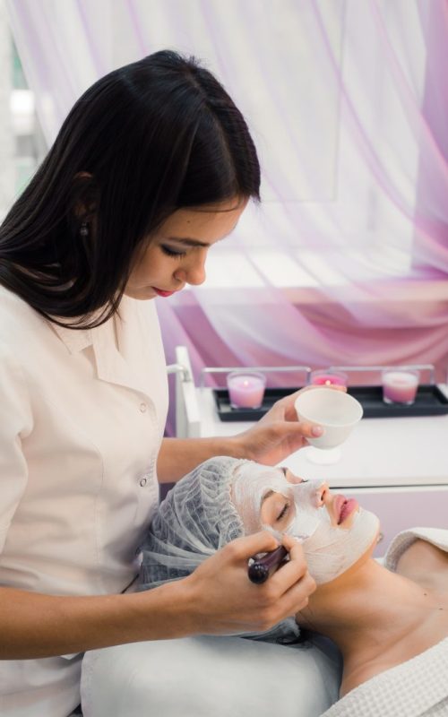 Spa concept. Young woman with nutrient facial mask in beauty salon